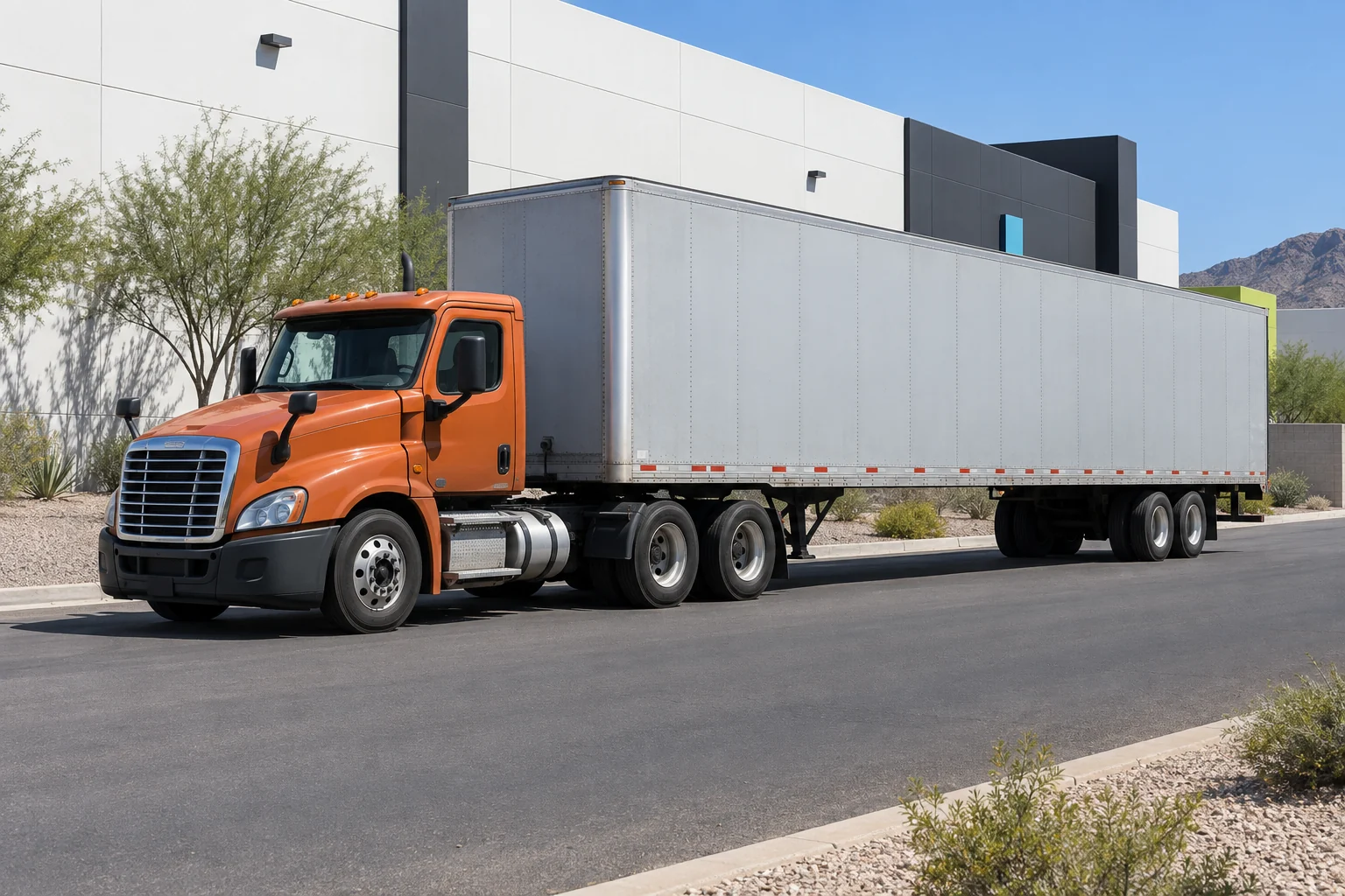 Unbranded orange day-cab tractor coupled to a gray dry-van trailer in a Phoenix industrial setting